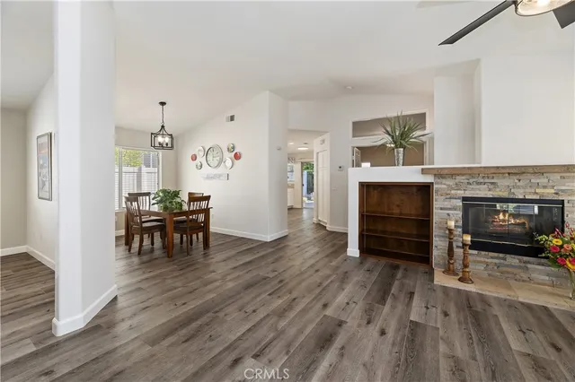 a view of a livingroom with a fireplace a ceiling fan and wooden floor