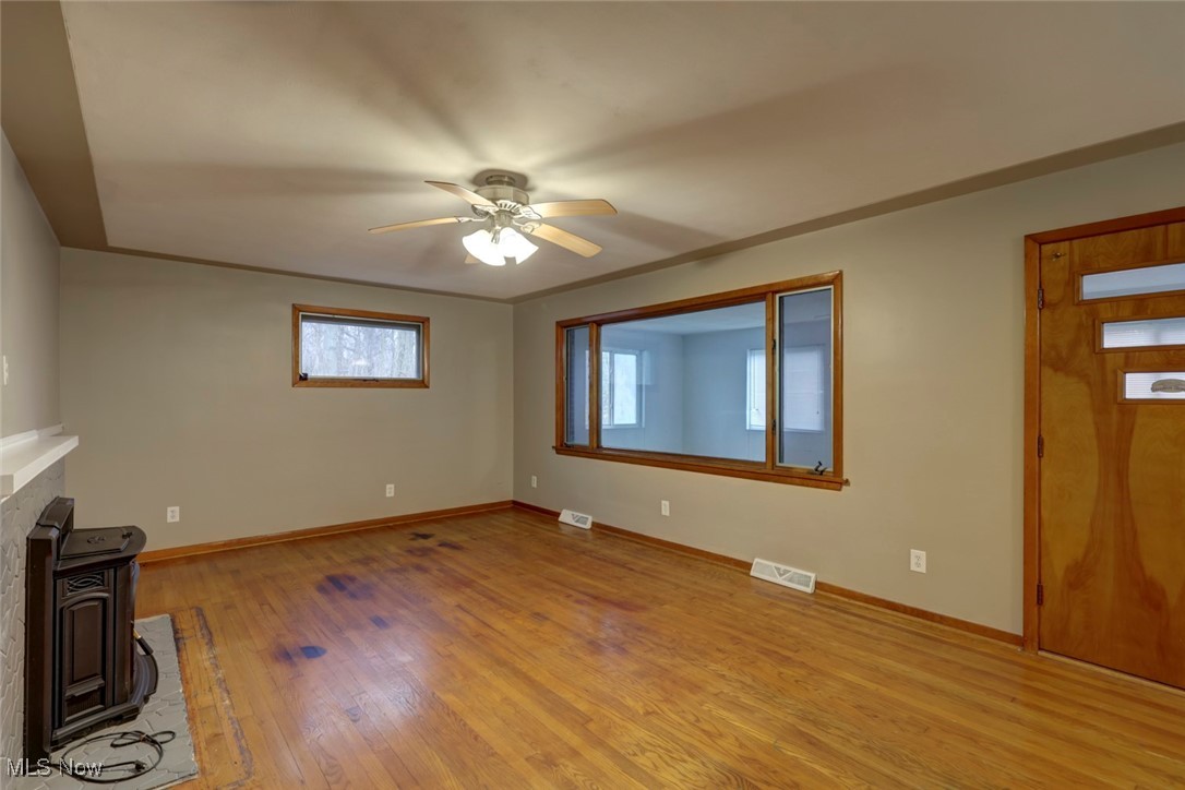 8104 Barnes Road Vermilion, OH 44089 - Photo 7 of 40 Unfurnished living room featuring ceiling fan, a wood pellet stove, and light hardwood flooring