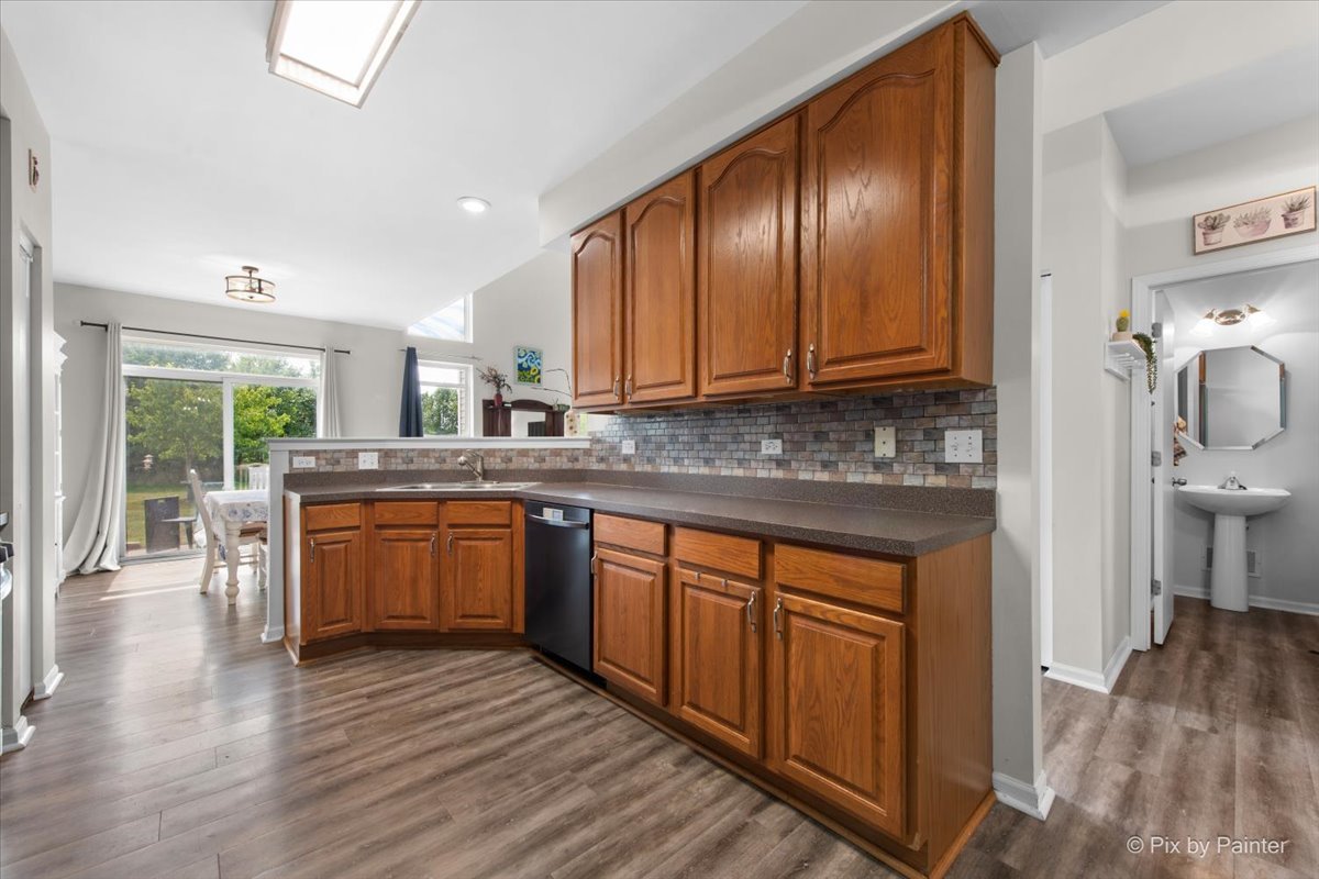 1033 Key Largo Drive Romeoville, IL 60446 - Photo 7 of 30 a kitchen with stainless steel appliances granite countertop wooden cabinets a stove top oven a sink and dishwasher with wooden floor
