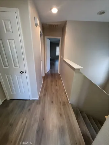 a view of a hallway with wooden floor and staircase
