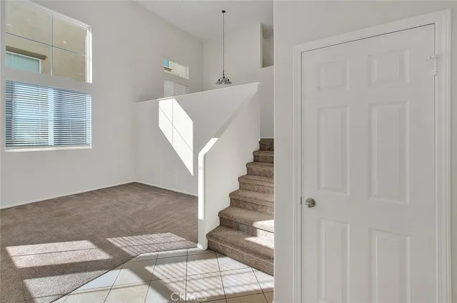 a view of an empty room with window and chandelier fan