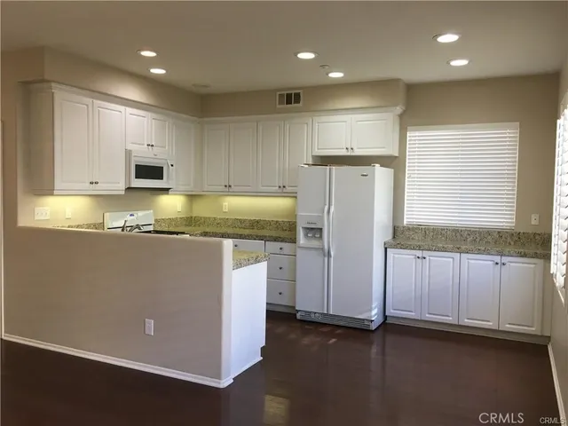 a kitchen with stainless steel appliances granite countertop a refrigerator sink and white cabinets