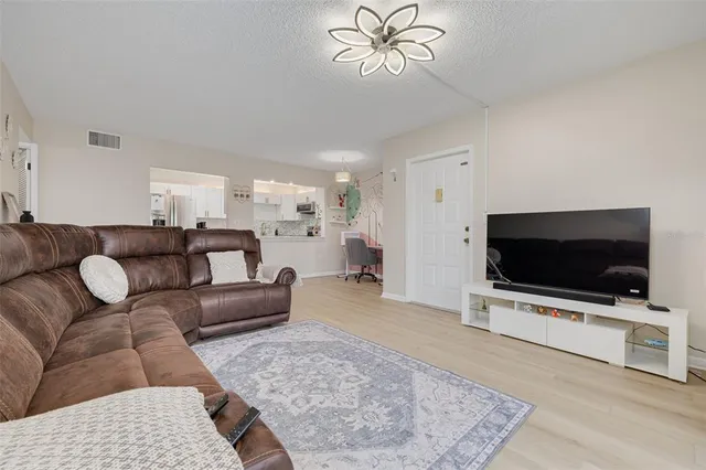 a living room with furniture two large window and a flat screen tv