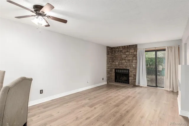 a view of a livingroom with a fireplace a ceiling fan and windows