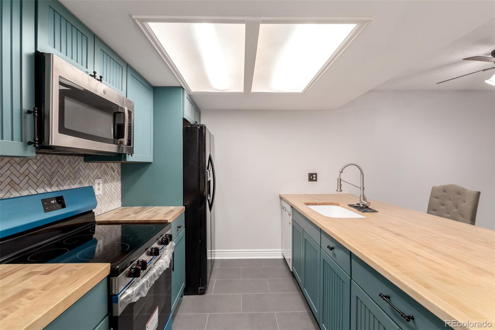 401 South Kalispell Way, Unit 104 Aurora, CO 80017 - Photo 6 of 29 a kitchen with stainless steel appliances a stove sink and microwave