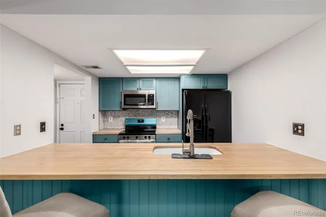 a kitchen with stainless steel appliances kitchen island sink refrigerator and microwave