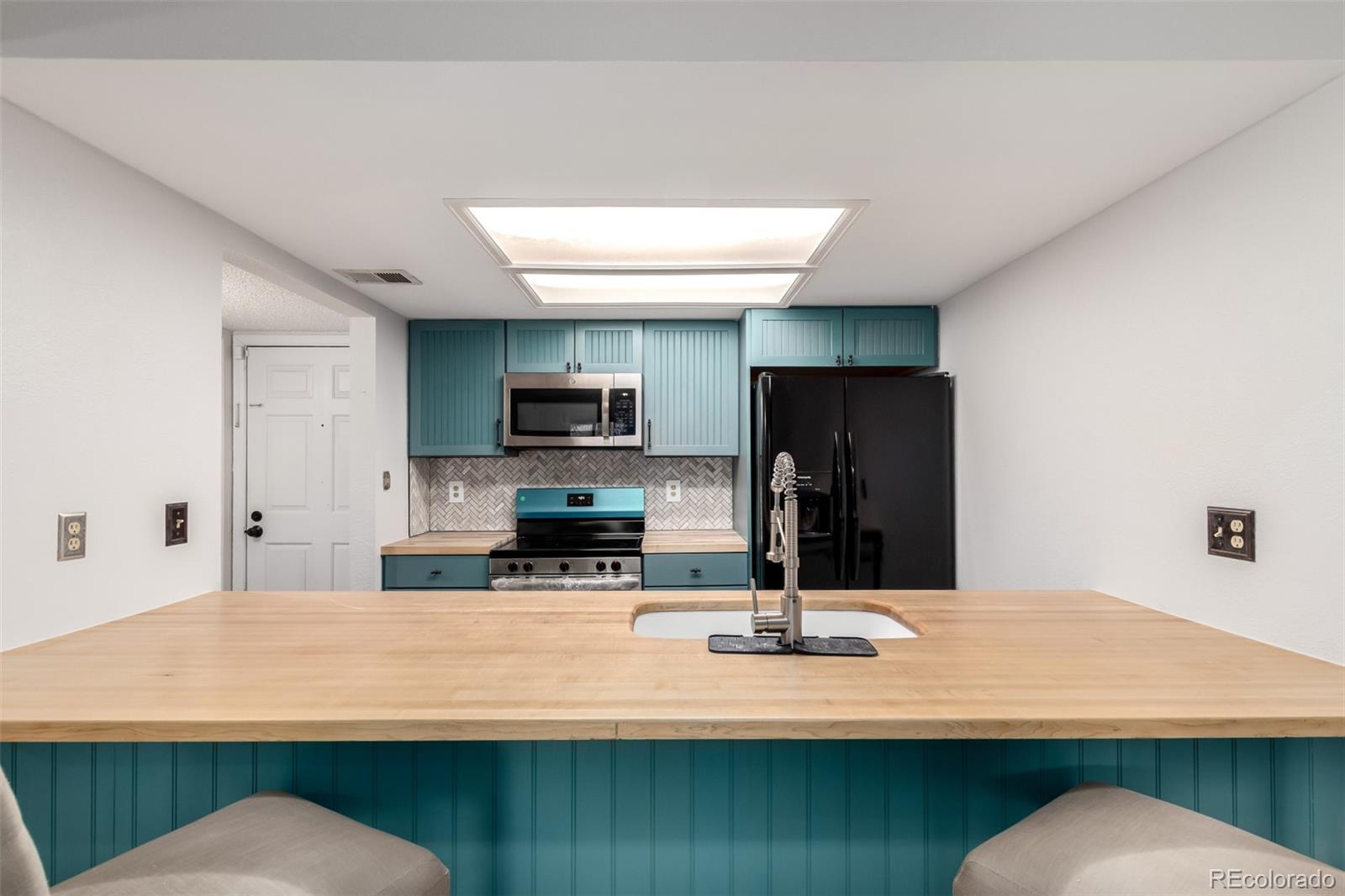 401 South Kalispell Way, Unit 104 Aurora, CO 80017 - Photo 8 of 29 a kitchen with stainless steel appliances kitchen island sink refrigerator and microwave