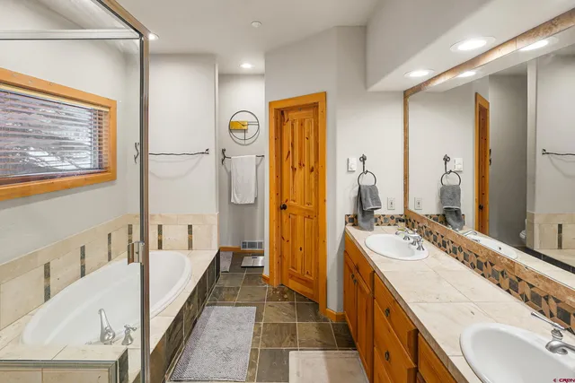 a spacious bathroom with a tub sink shower and mirror