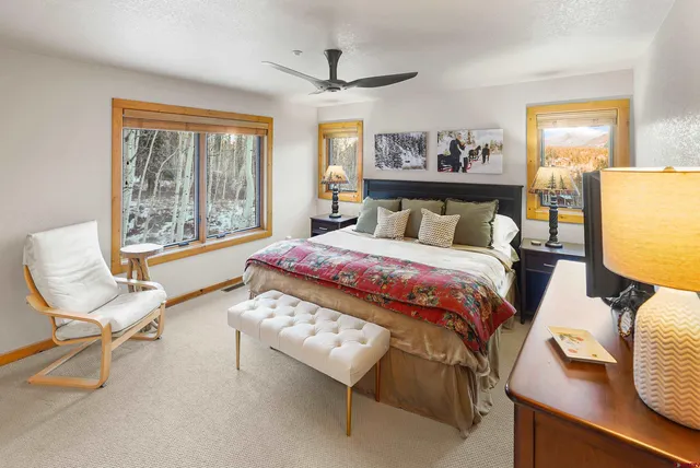 a bedroom with a bed a chair and a large window