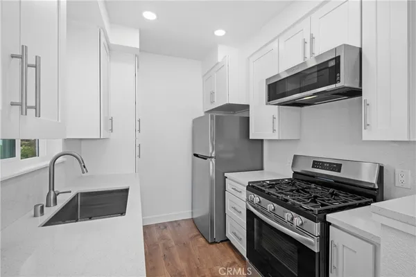 a kitchen with stainless steel appliances a sink a stove and a refrigerator with wooden floor