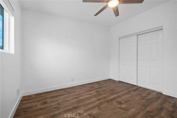 an empty room with a ceiling fan and wooden floor