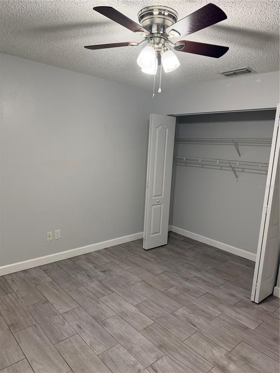 2701 Northeast 10th Street, Unit 802 Ocala, FL 34470 - Photo 4 of 16 an empty room with wooden floor chandelier fan and closet