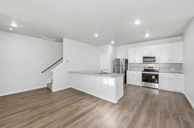 a kitchen with white cabinets stainless steel appliances and wooden floor