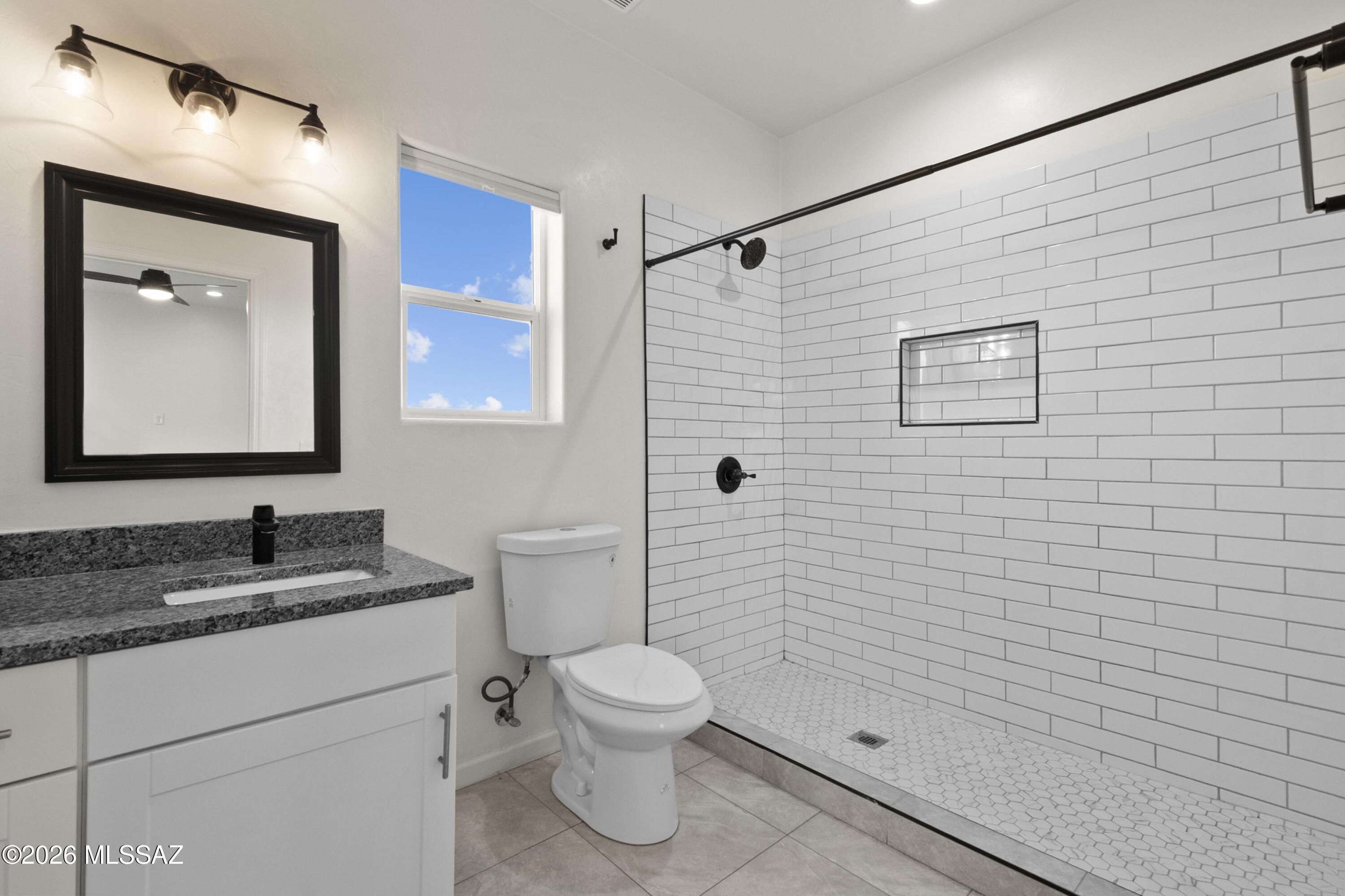 1785 Dove Court Rio Rico, AZ 85648 - Photo 19 of 31 a bathroom with a granite countertop toilet sink and mirror