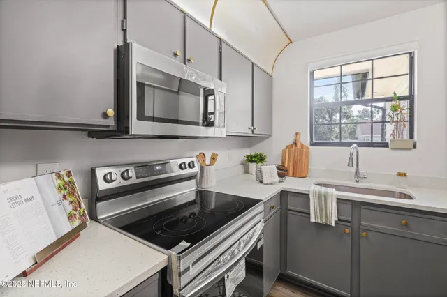 a kitchen with stainless steel appliances a sink a stove cabinets and a window