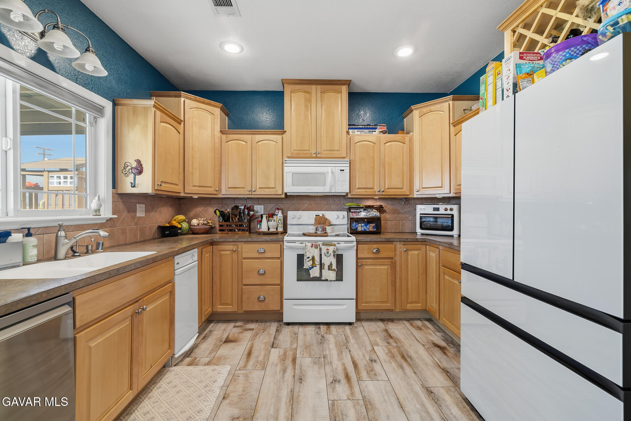 49945 80th Street West Lancaster, CA 93536 - Photo 10 of 38 a kitchen with stainless steel appliances granite countertop a refrigerator a sink dishwasher and white cabinets with wooden floor