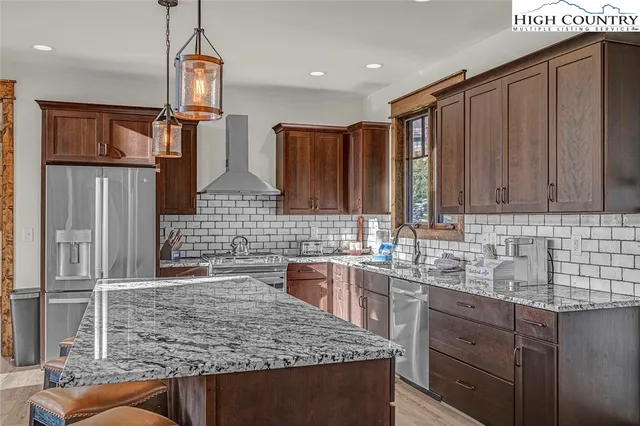 a kitchen with stainless steel appliances granite countertop a sink refrigerator and cabinets