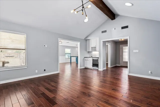 a view of empty room with wooden floor and window