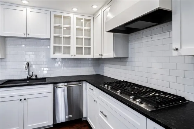 a kitchen with granite countertop white cabinets and black stove top oven