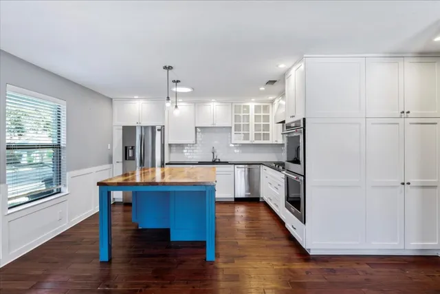 a large kitchen with a table chairs wooden floor and a window