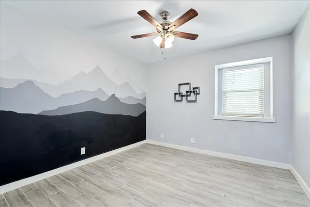 a view of a big room with wooden floor and a ceiling fan