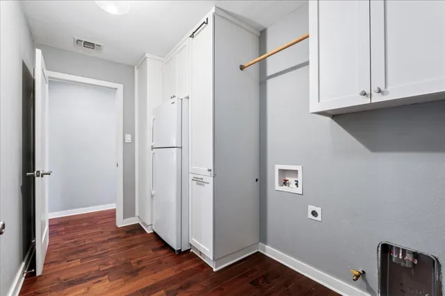 a view of an empty room with wooden floor and cabinets