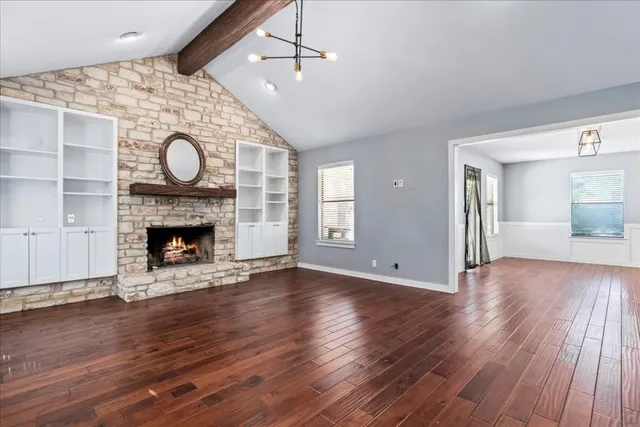 a view of an empty room with wooden floor and fireplace