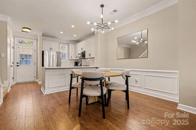 a kitchen with kitchen island a dining table chairs refrigerator and cabinets