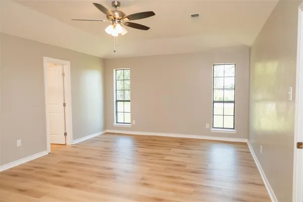 a view of an empty room with window and wooden floor