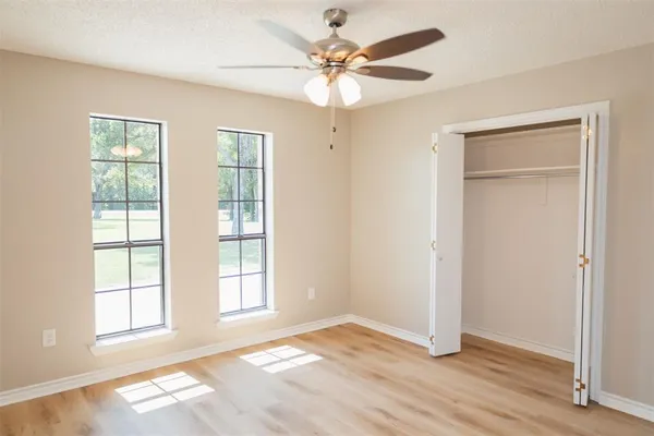 a view of an empty room with chandelier fan and a window