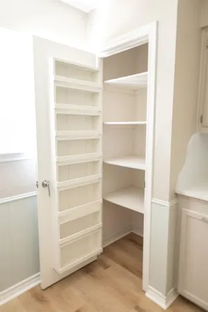 a view of an empty room with wooden floor and a ceiling fan