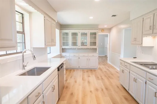 a large kitchen with a sink large window stainless steel appliances and cabinets
