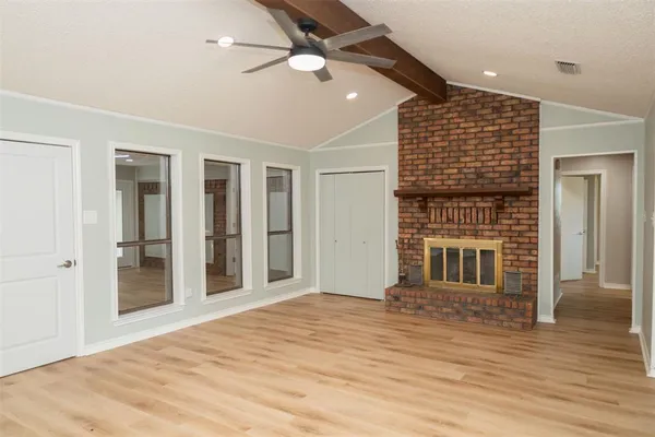 a view of an empty room with wooden floor and a fireplace