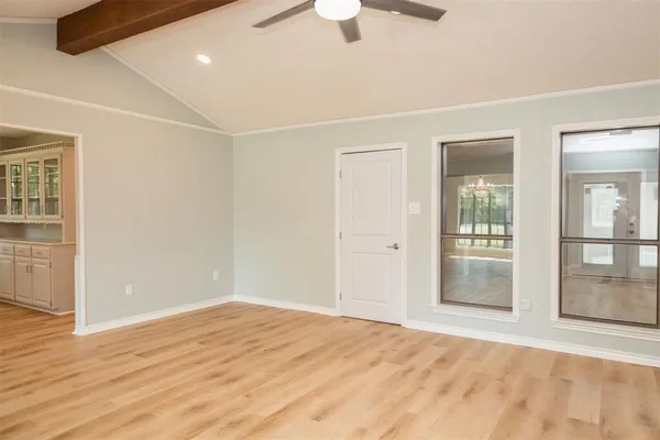 a view of an empty room with wooden floor and a window