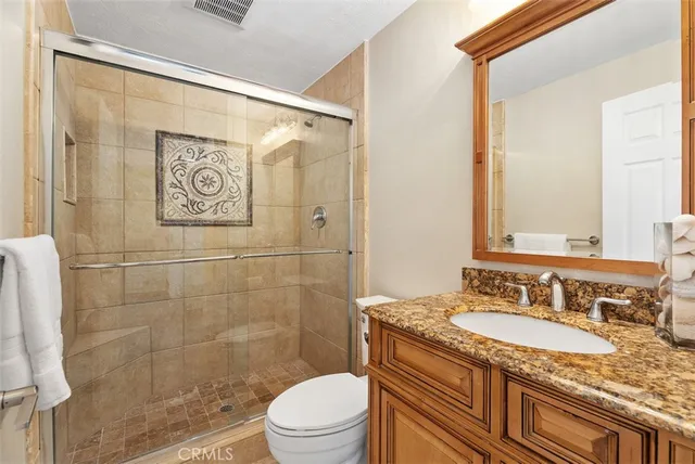 a bathroom with a granite countertop sink toilet and shower