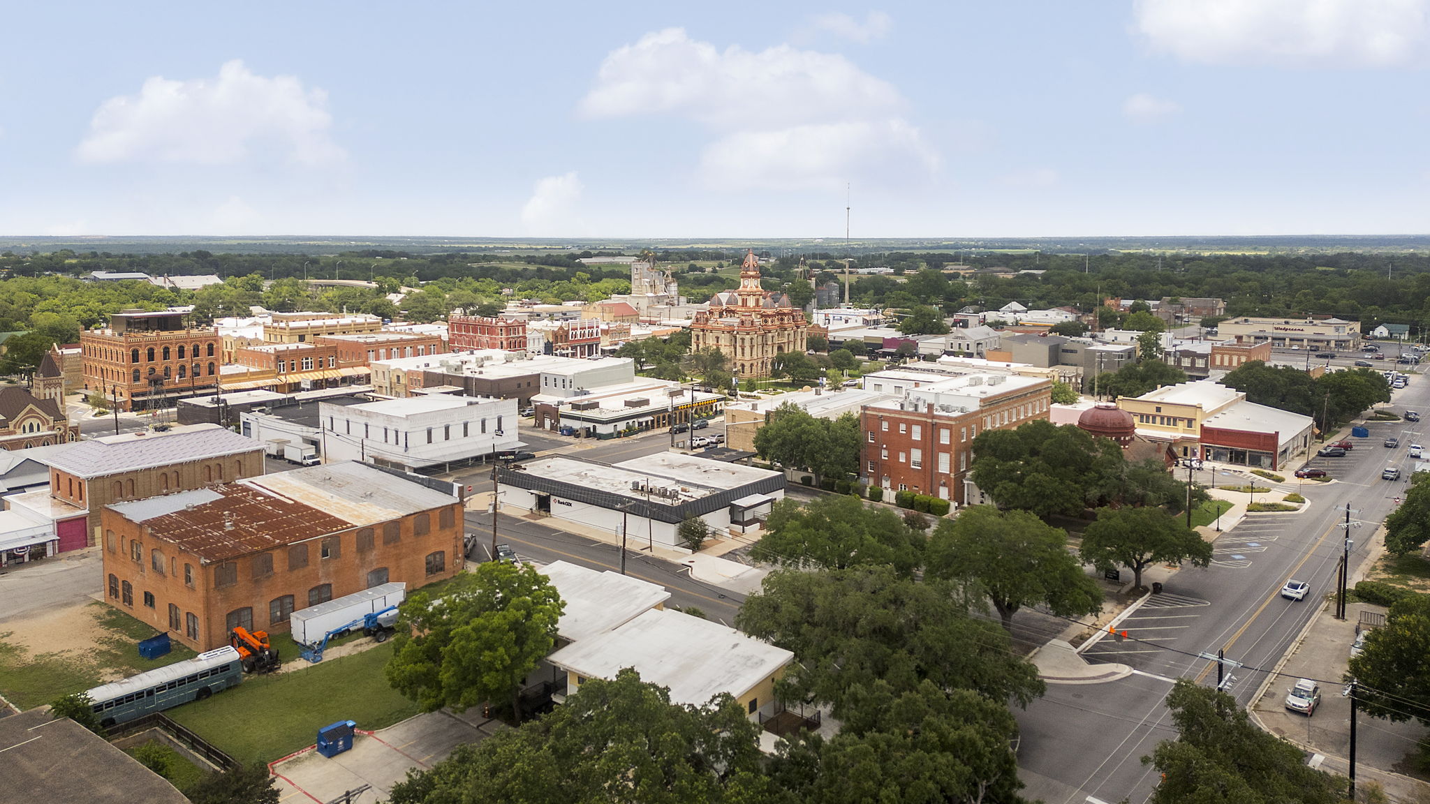 400 Hackberry Street Lockhart, TX 78644 - Photo 35 of 40 An aerial perspective showcases a bustling downtown district with varied architecture and mature trees lining the streets.