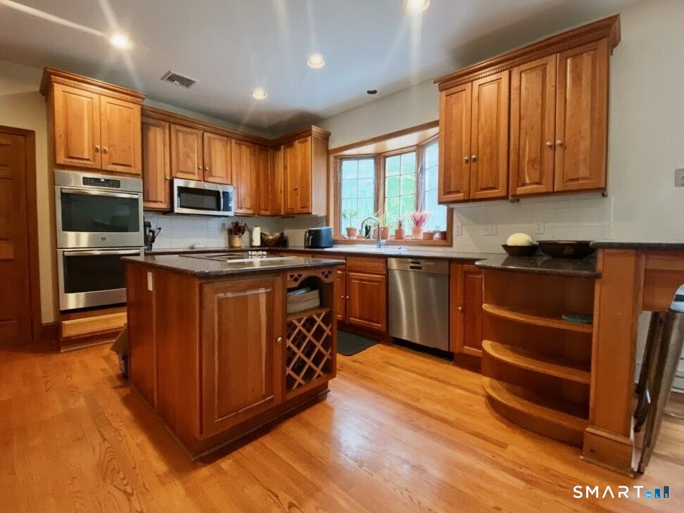 12 Carriage Hill Road Woodbridge, CT 06525 - Photo 8 of 24 a kitchen with stainless steel appliances granite countertop wooden cabinets a sink a stove a refrigerator and island with wooden floor