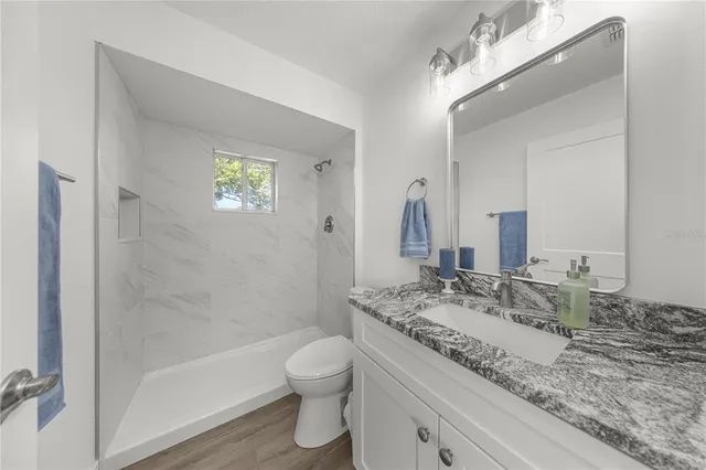 a bathroom with a granite countertop sink a toilet and shower