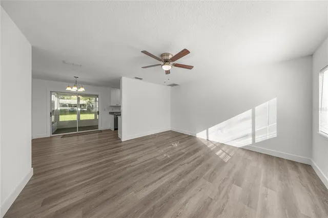 an empty room with wooden floor and ceiling fan