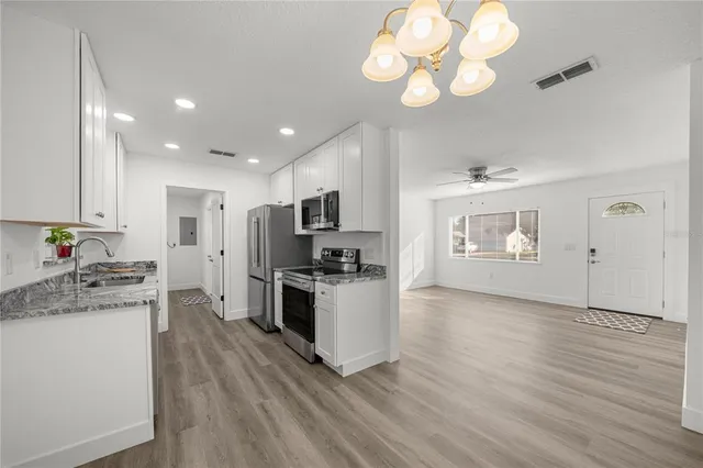 a large kitchen with stainless steel appliances granite countertop a stove top oven a refrigerator a sink and dishwasher with wooden floor