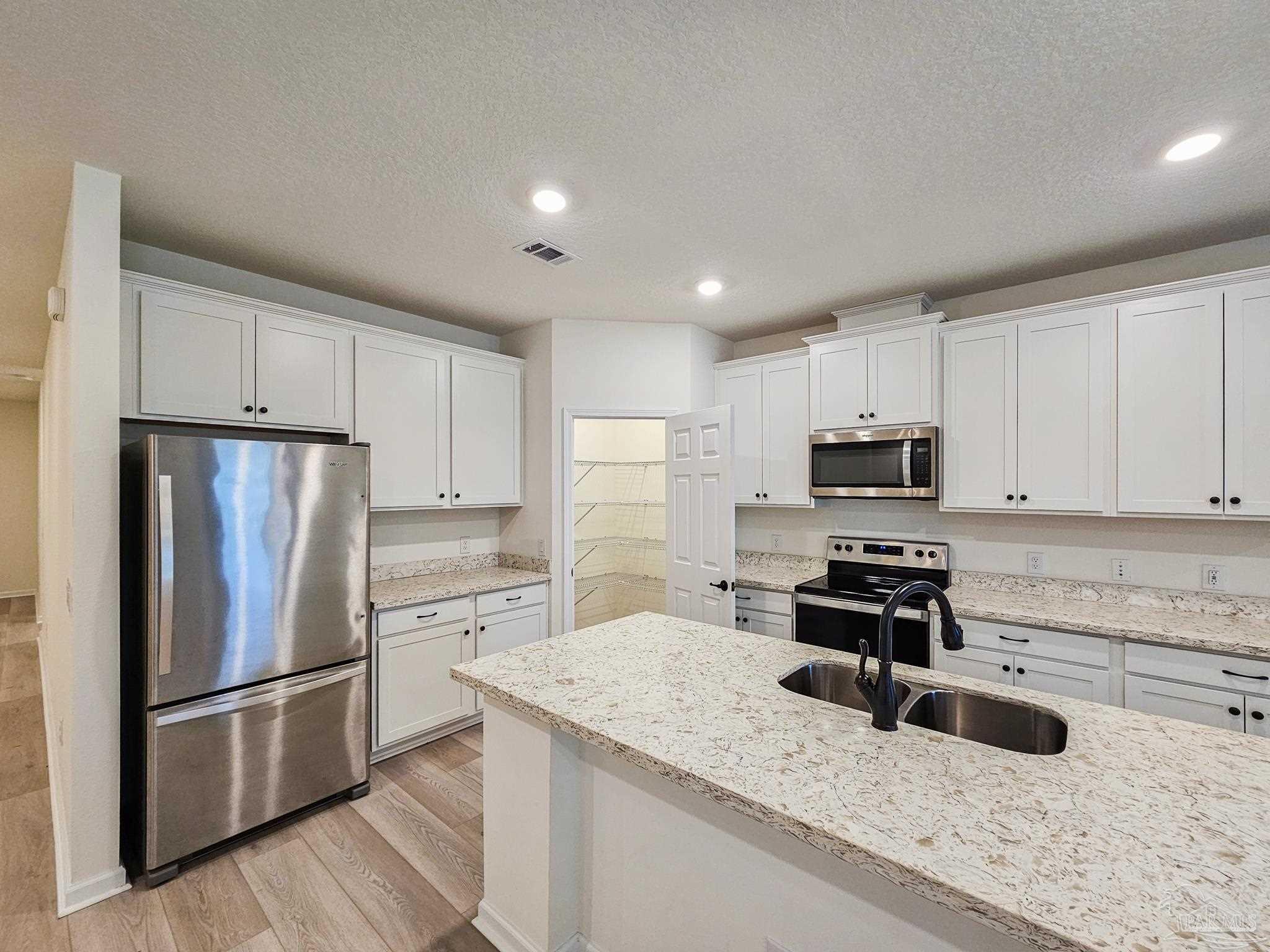 4149 Upper Walk Lane Milton, FL 32583 - Photo 9 of 43 a kitchen with granite countertop a refrigerator a sink a stove a microwave and wooden cabinets