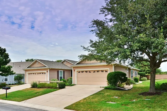 a view of a house with a big yard plants and large trees