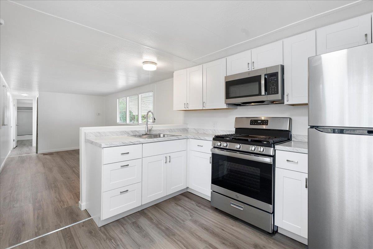 a kitchen with stainless steel appliances white cabinets a sink and a stove