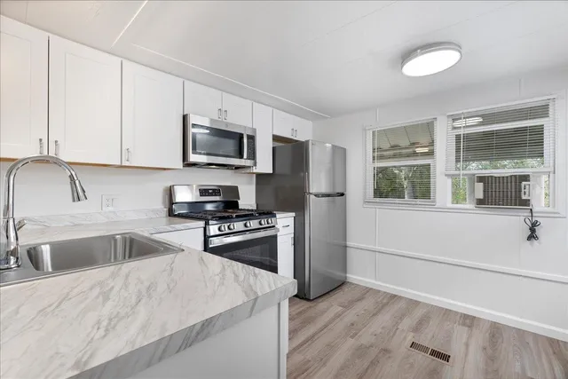 a kitchen with stainless steel appliances granite countertop a stove a sink and a refrigerator