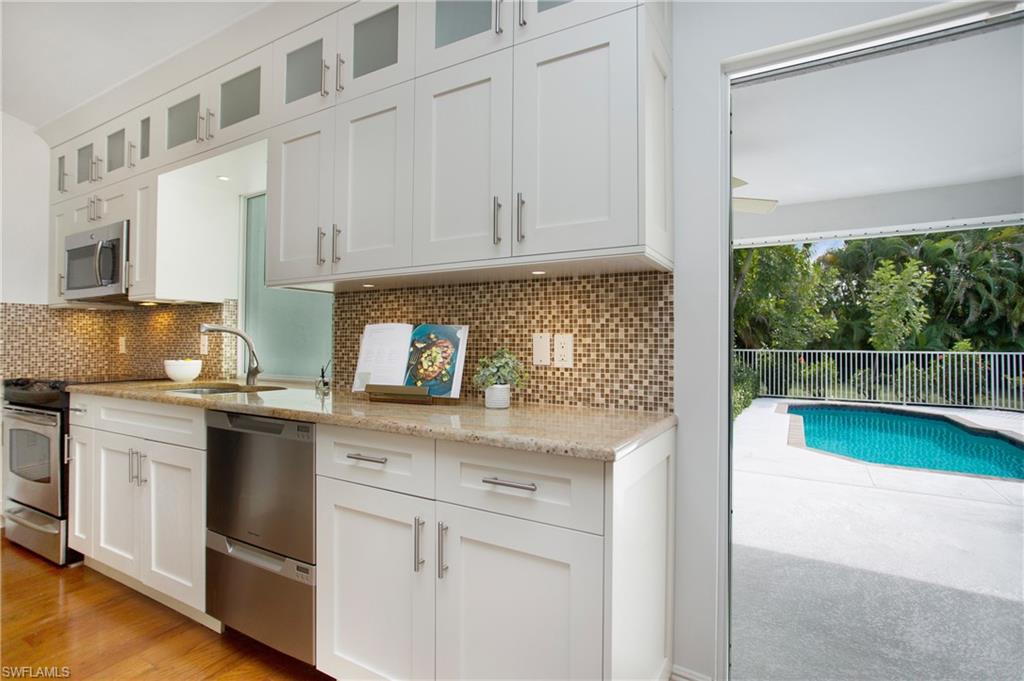 1534 Northgate Drive Naples, FL 34105 - Photo 10 of 50 a kitchen with granite countertop white cabinets and white appliances
