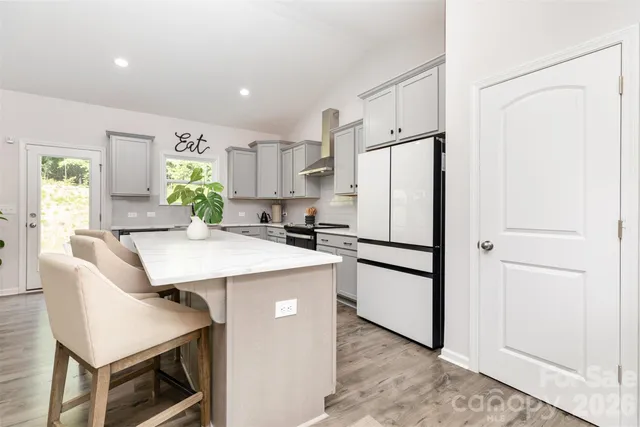 a kitchen with a refrigerator a stove a sink and a dining table with wooden floor