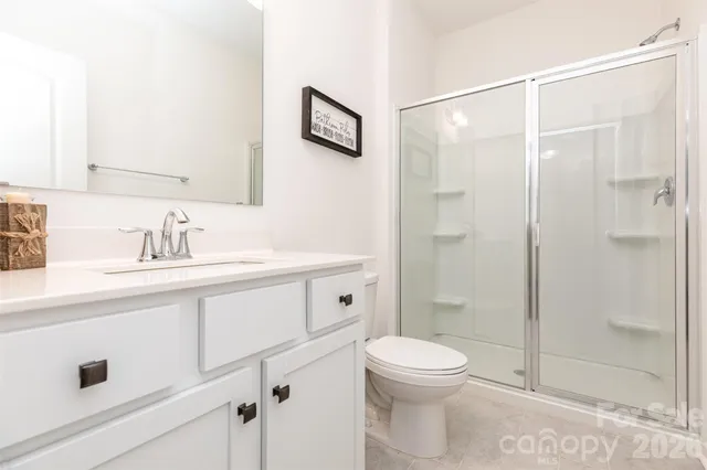 a bathroom with a shower sink vanity mirror and toilet