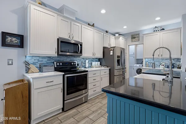 a kitchen with stainless steel appliances granite countertop a stove a sink dishwasher a refrigerator and a microwave