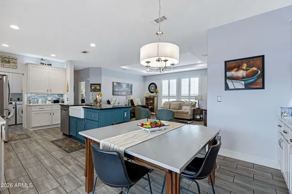 a view of a dining room with furniture a kitchen and chandelier