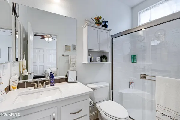 a bathroom with a sink a toilet a mirror and shower